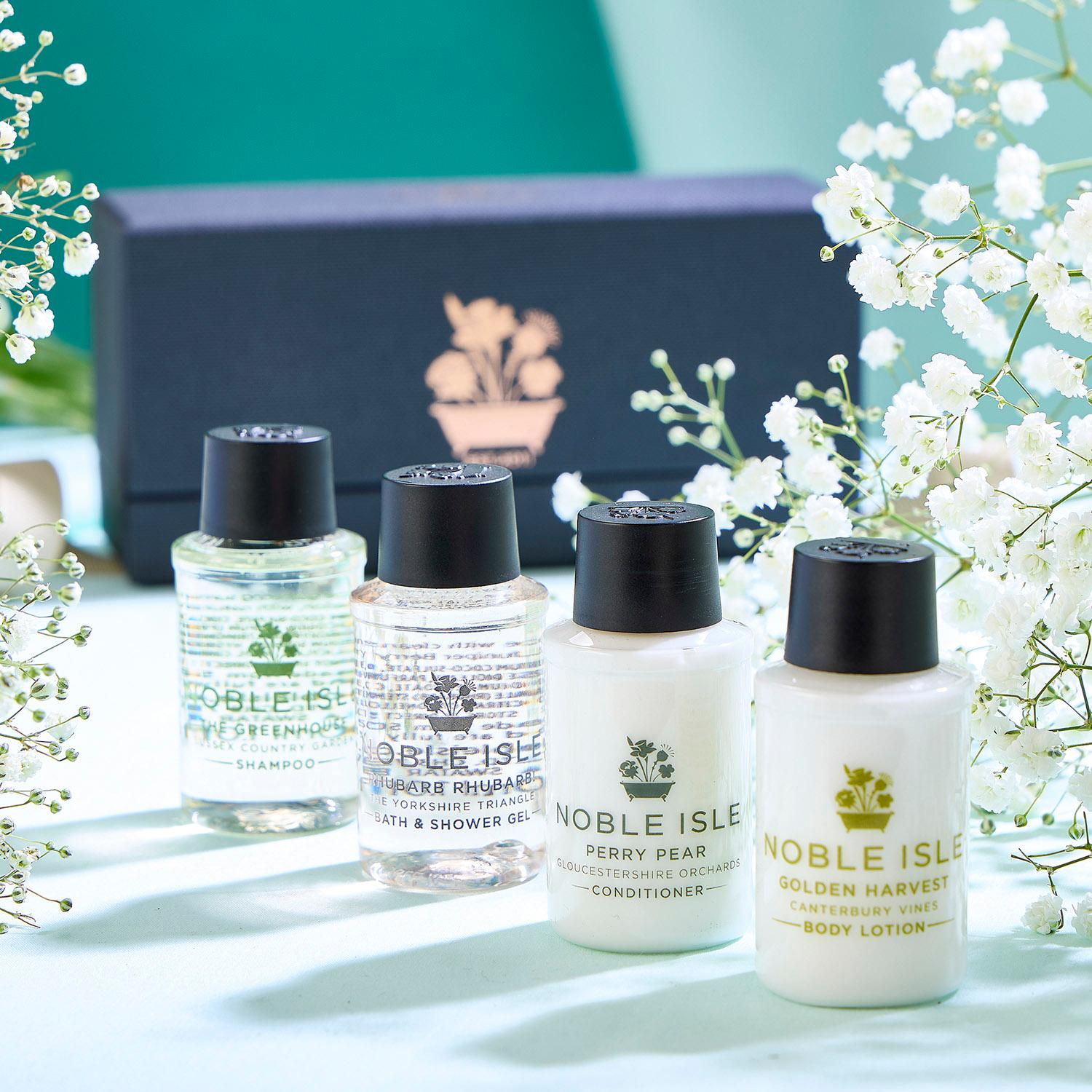 The Pantry Gift Set, with four 30ml bottles of Bath & shower gel, body lotion, shampoo and conditioner, surrounded by flowers.