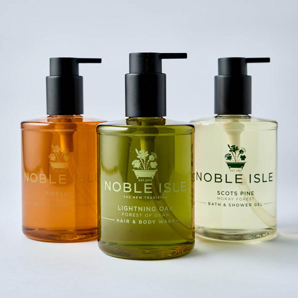 Three bottles of Noble Isle bath and shower gels with a Lightning Oak at the from and a Whisky & Water and Scots Pine behind.